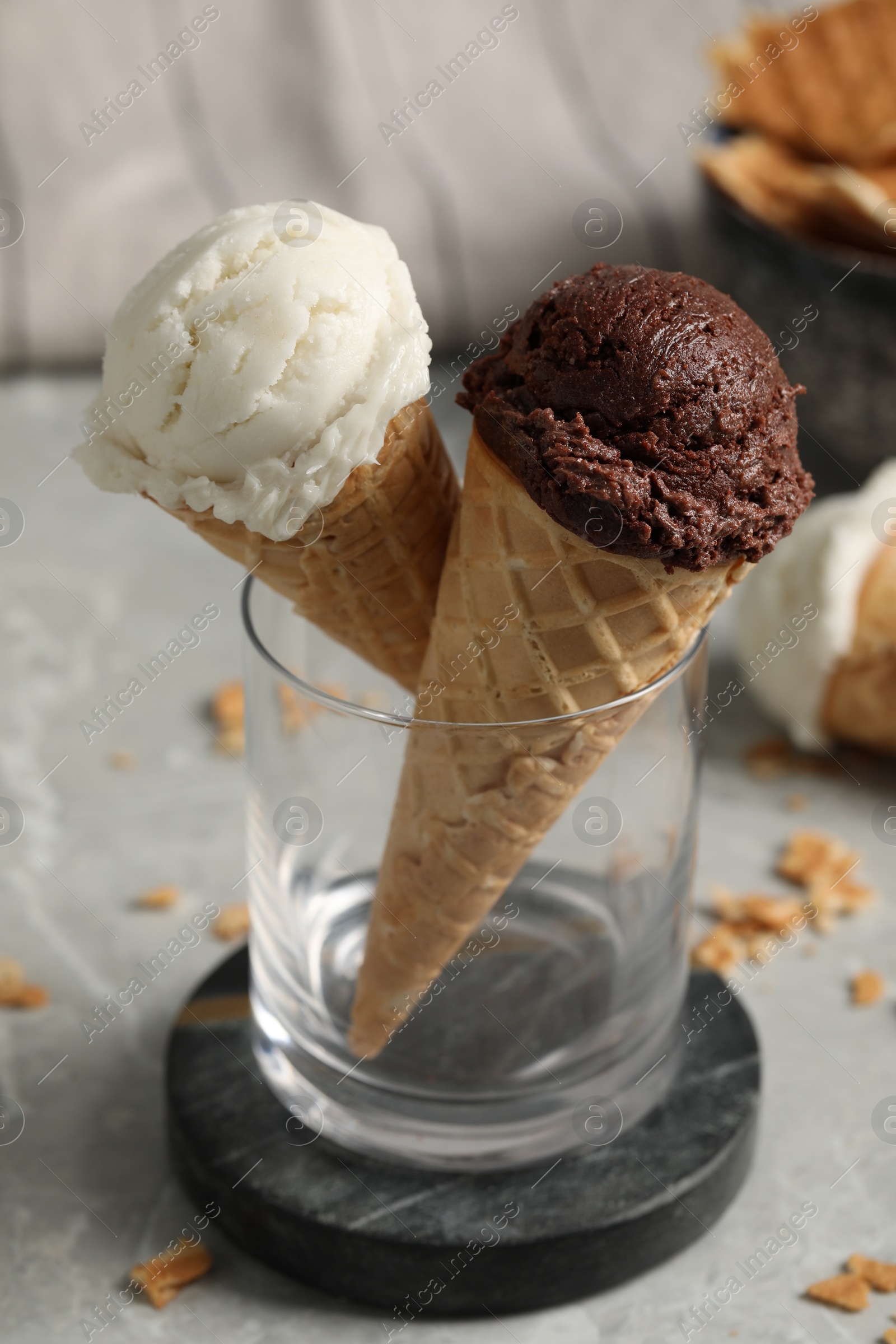 Photo of Tasty ice cream scoops in waffle cones on grey marble table, closeup