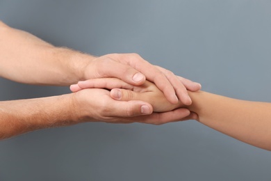 Photo of Man holding woman's hand on gray background, closeup. Concept of support and help