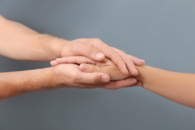 Man holding woman's hand on gray background, closeup. Concept of support and help