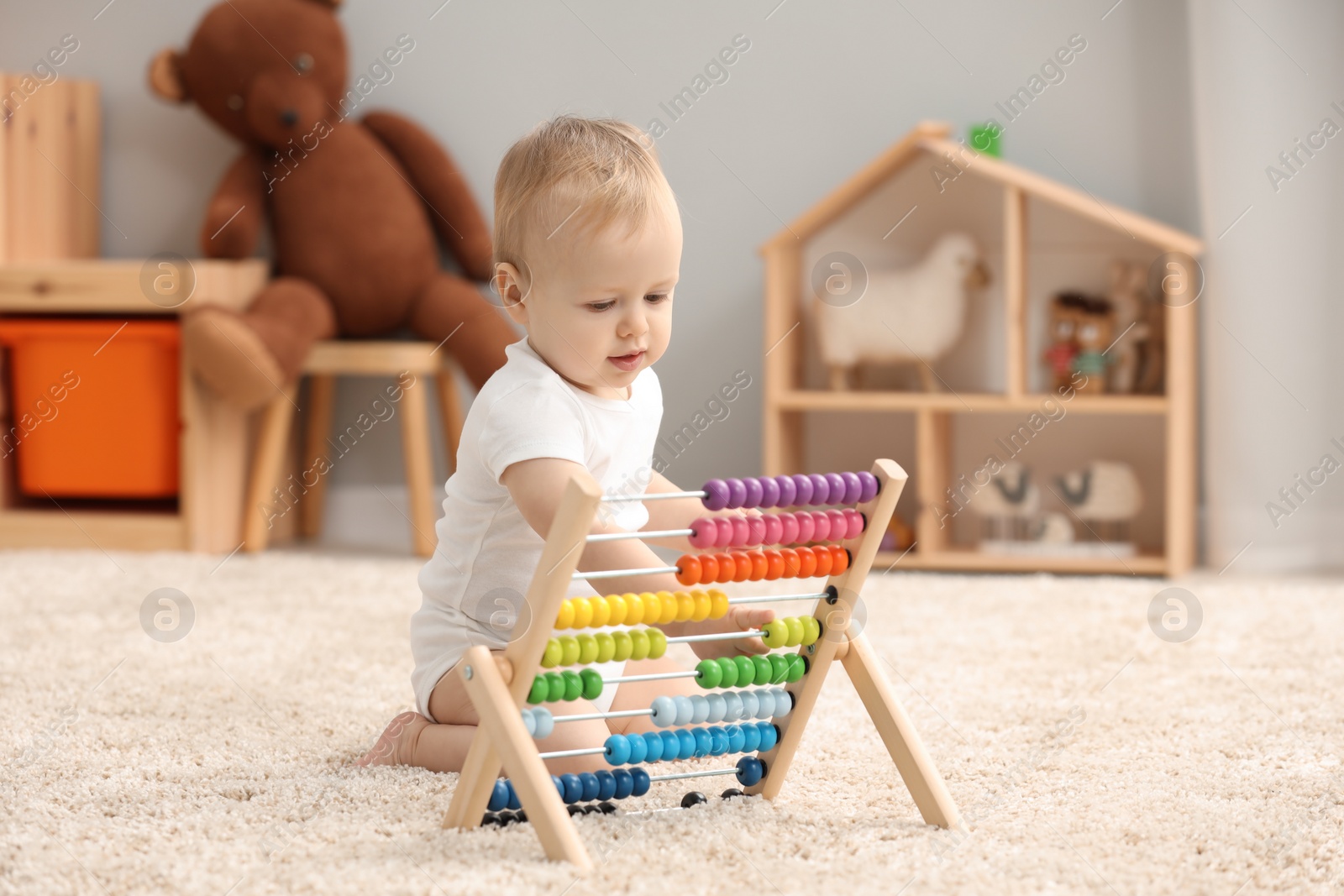 Photo of Children toys. Cute little boy playing with wooden abacus on rug at home