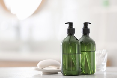 Green soap dispensers on white countertop in bathroom. Space for text