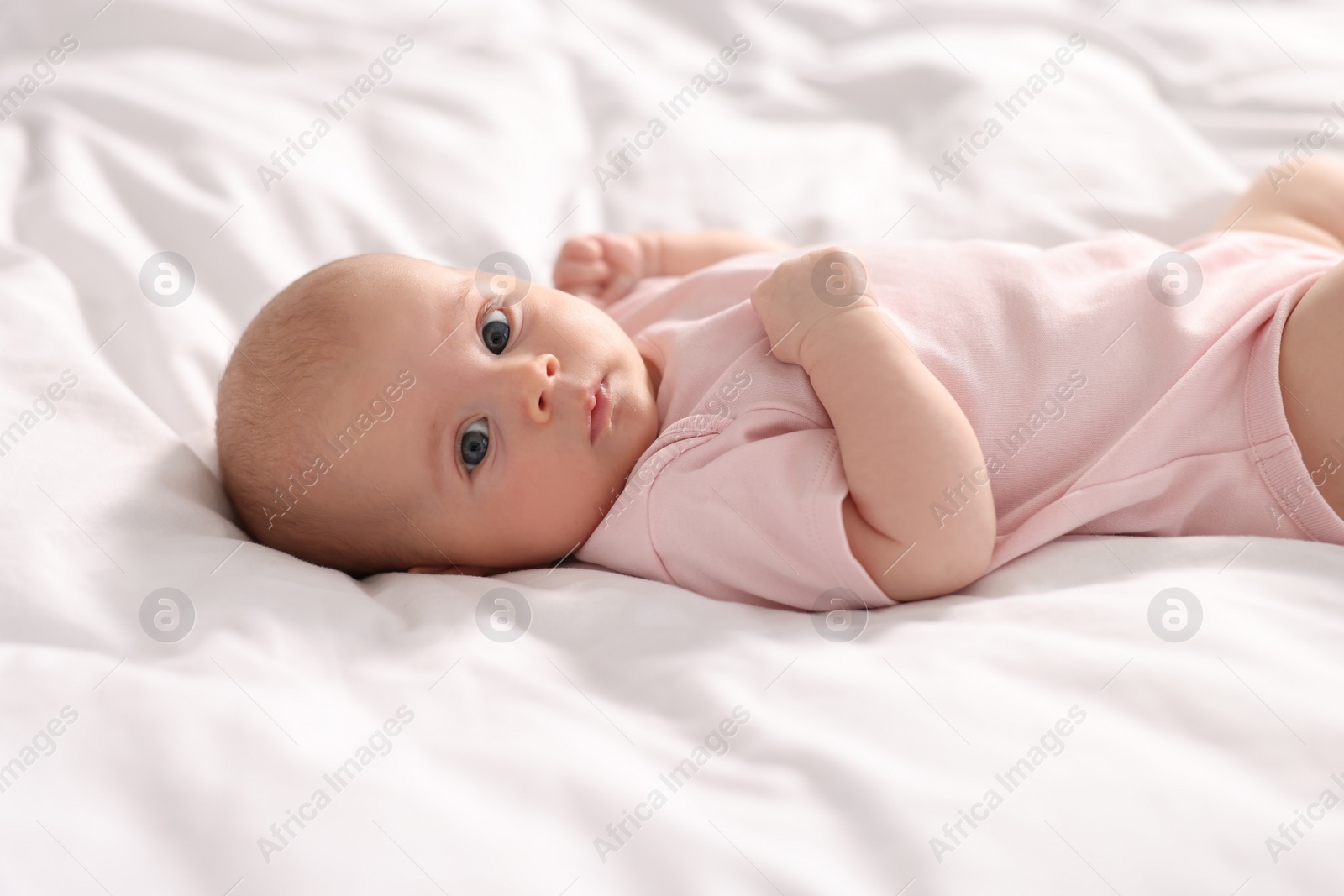 Photo of Cute little baby lying on white sheets