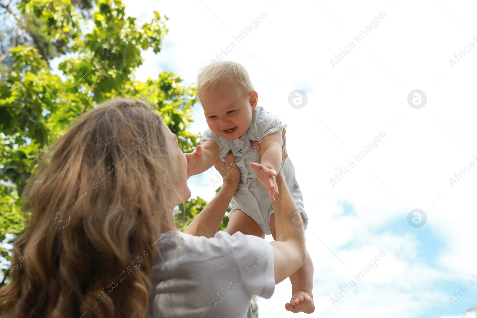 Photo of Mother with her cute baby spending time together outdoors, low angle view. Space for text