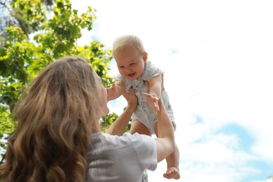 Photo of Mother with her cute baby spending time together outdoors, low angle view. Space for text