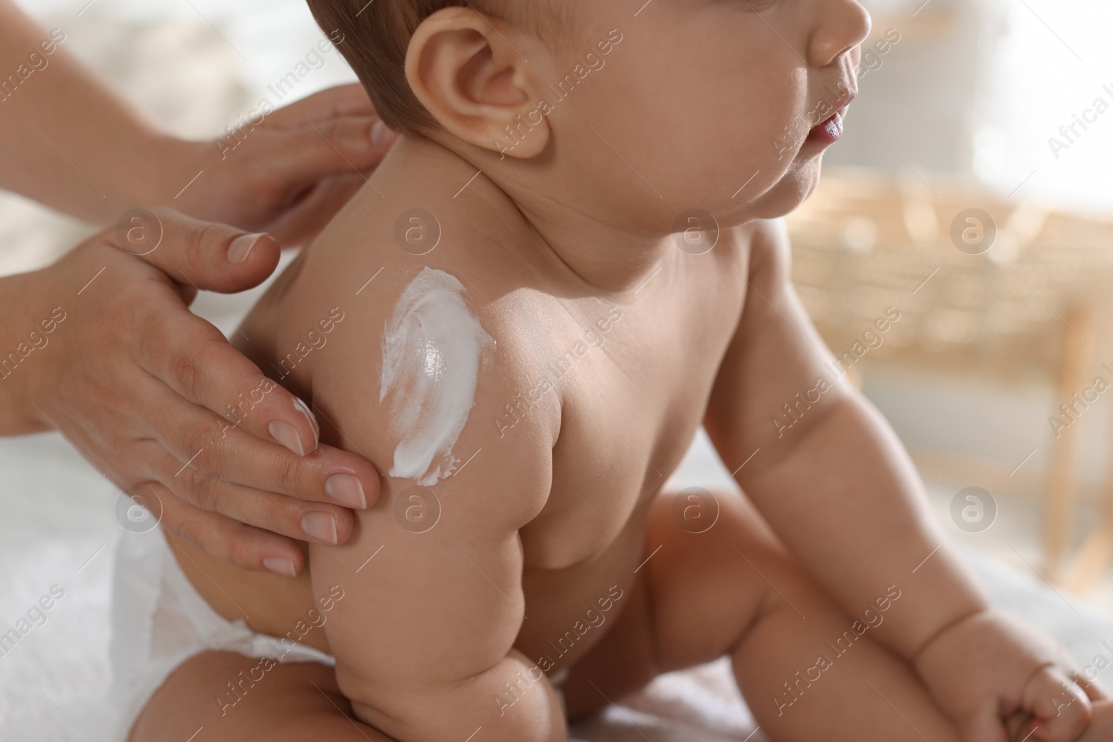 Photo of Mother applying body cream on her little baby at home, closeup