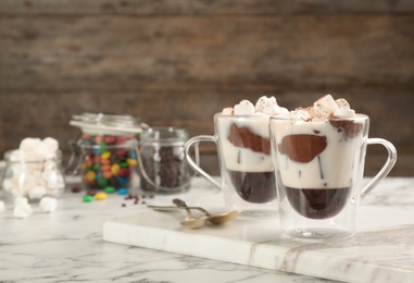 Photo of Cups of chocolate dessert with marshmallows on marble table. Space for text