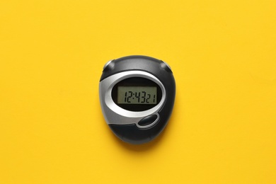 Modern stopwatch on yellow background, top view