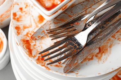 Stack of dirty dishes with cutlery, closeup