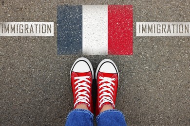 Image of Immigration. Woman standing on asphalt near flag of France, top view