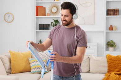 Spring cleaning. Man with headphones and mop in living room