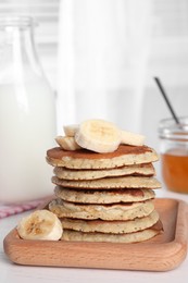 Photo of Plate of banana pancakes with honey and milk on white wooden table