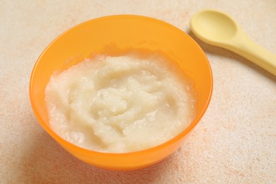 Baby food. Bowl with cauliflower puree served on beige textured table, closeup