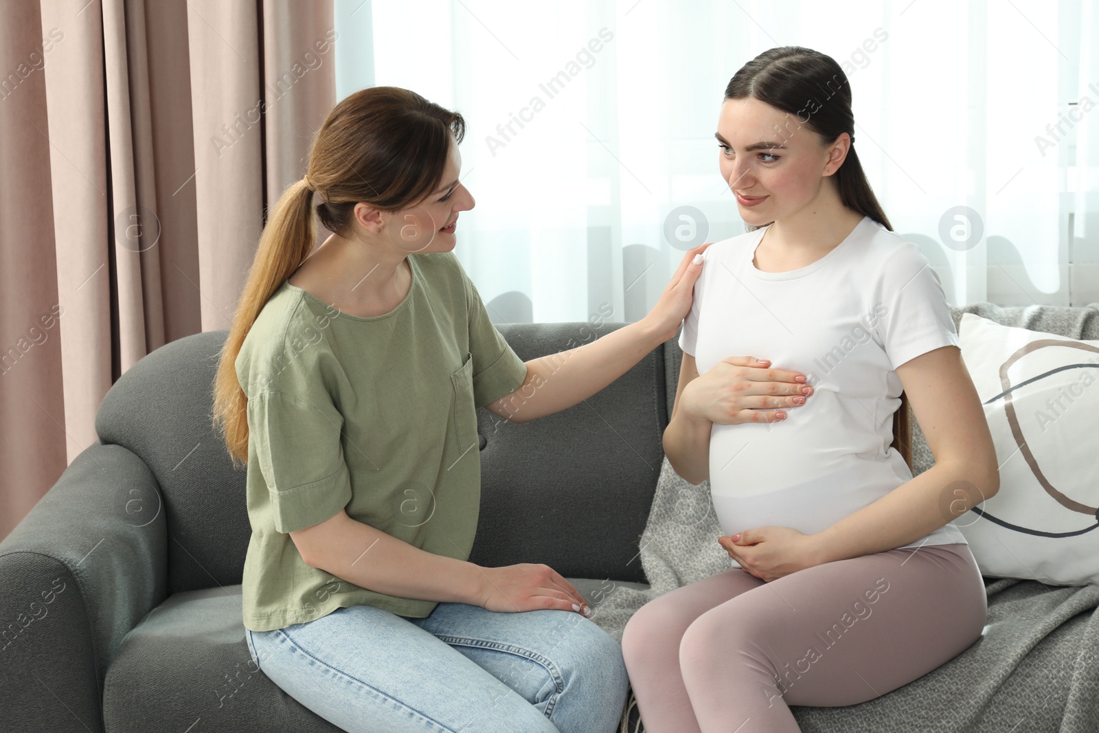 Photo of Doula taking care of pregnant woman on sofa at home. Preparation for child birth