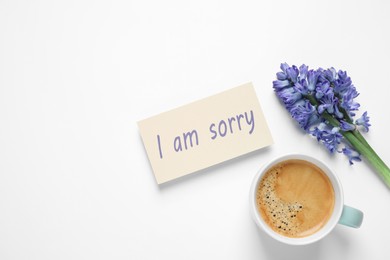 Image of Card with phrase I Am Sorry, hyacinth flowers and cup of coffee on white background, flat lay. Space for text