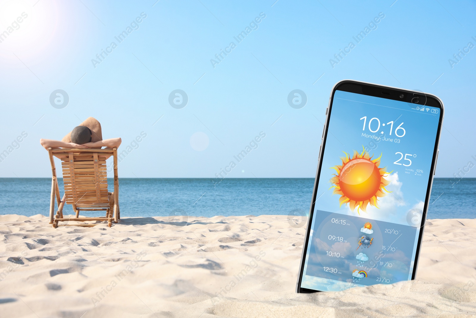 Image of Young woman relaxing in deck chair on sandy beach and smartphone with open weather forecast app 