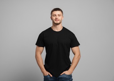 Man wearing black t-shirt on light grey background. Mockup for design