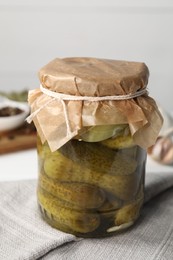 Photo of Tasty pickled cucumbers in jar on table