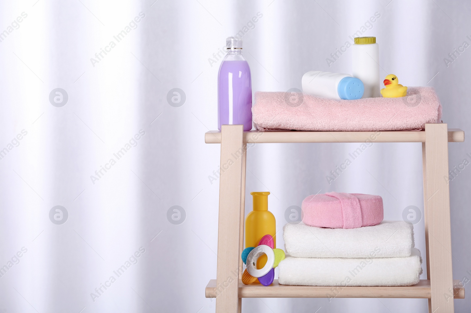 Photo of Shelving unit with different baby accessories on light background. Space for text