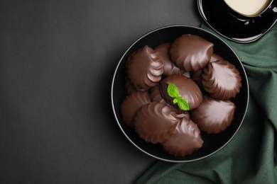 Delicious chocolate covered zephyrs with mint and coffee on black table, flat lay. Space for text