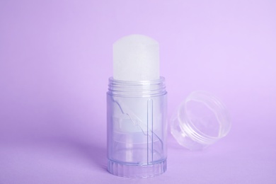 Photo of Natural crystal alum stick deodorant and cap on lilac background