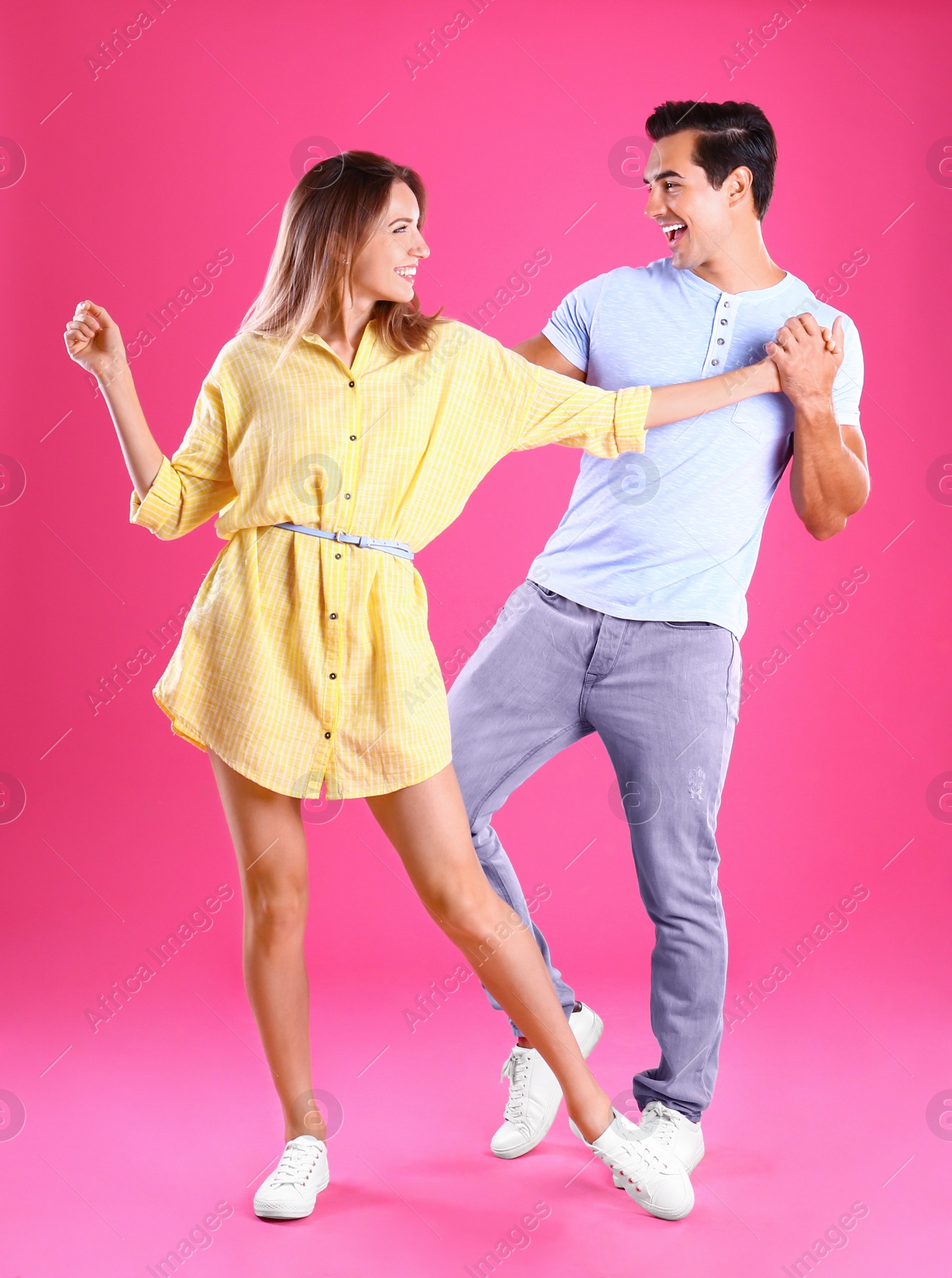 Photo of Beautiful young couple dancing on pink background