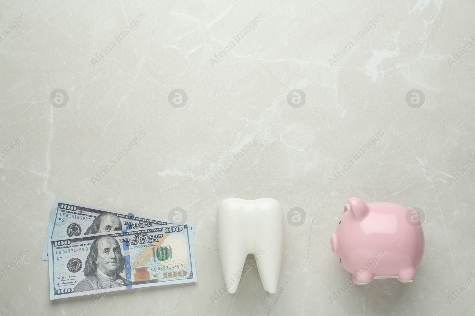 Photo of Ceramic model of tooth, piggy bank and dollar banknotes on light grey table, flat lay with space for text. Expensive treatment