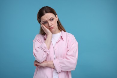 Portrait of sad woman on light blue background