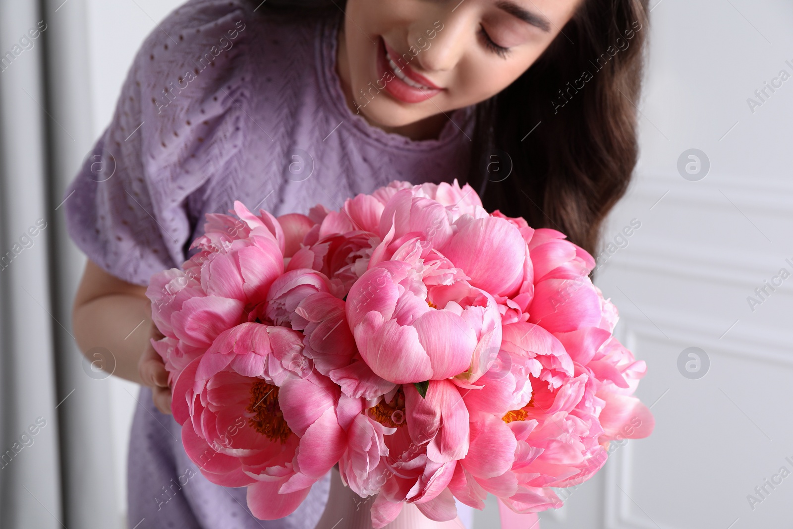 Photo of Young woman near bouquet of pink peonies indoors, closeup