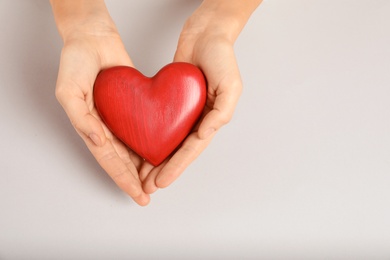 Photo of Woman holding decorative heart on light background, top view with space for text