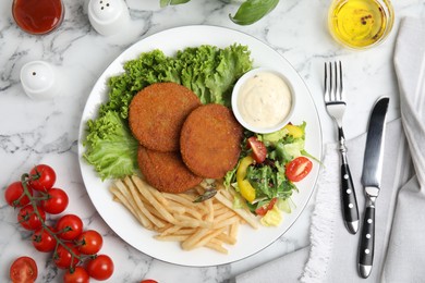 Delicious fried breaded cutlets with garnish served on white marble table, flat lay