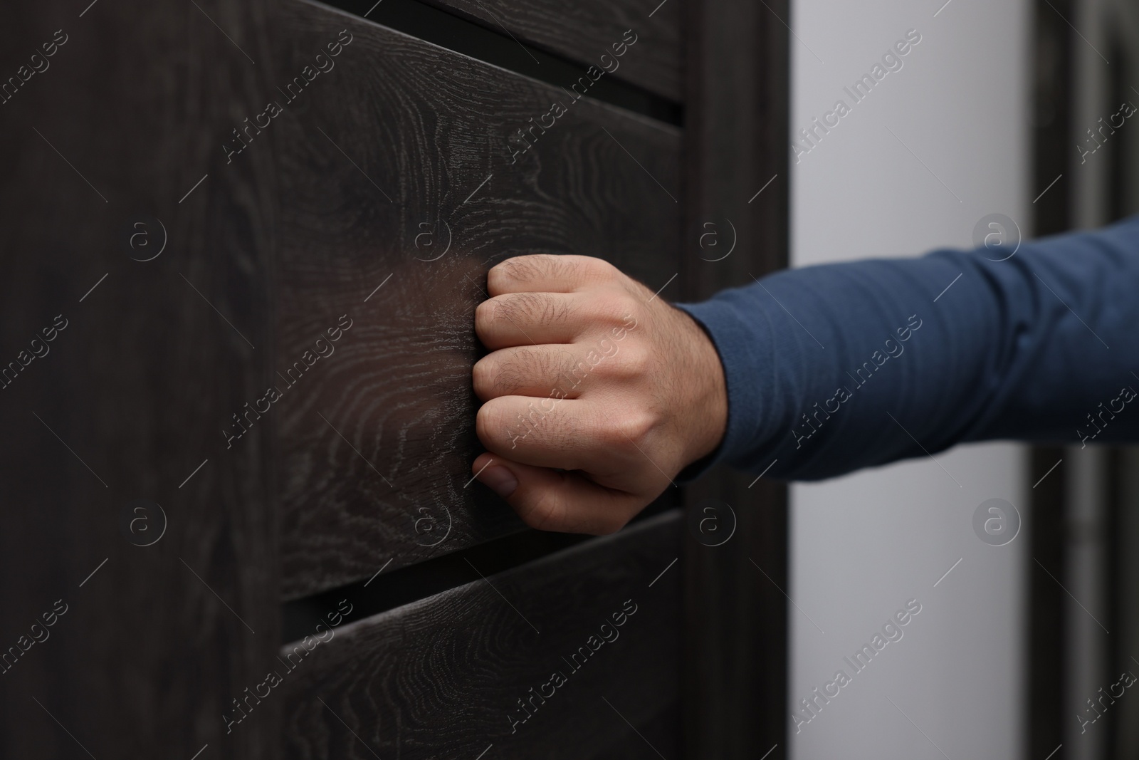 Photo of Collection agent knocking on wooden door, closeup