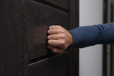 Collection agent knocking on wooden door, closeup