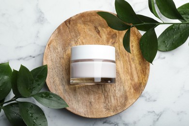Photo of Wooden plate with jar of organic cream and plant branches on white marble table