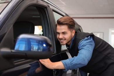 Young man near new car in dealership