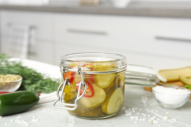Photo of Jar with pickled cucumbers on grey table in kitchen
