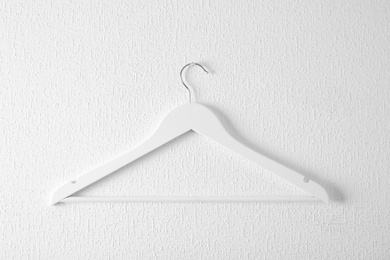 Photo of Empty clothes hanger on light wall. Wardrobe accessory