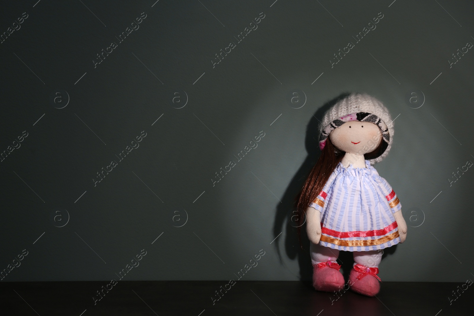 Photo of Abandoned doll on table against gray background. Time to visit child psychologist