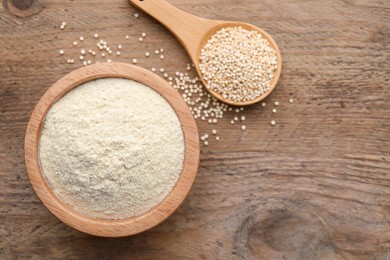 Photo of Quinoa flour in bowl and spoon with seeds on wooden table, flat lay