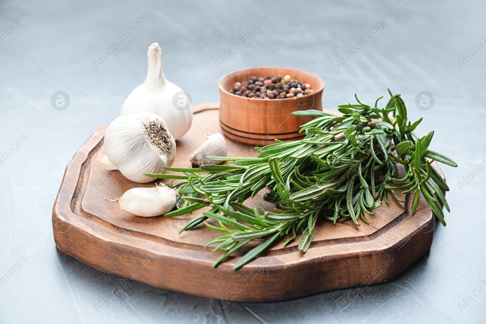 Photo of Fresh rosemary, garlic and pepper on grey table