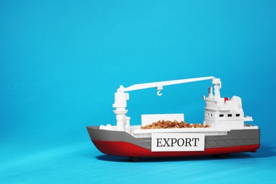 Photo of Toy cargo vessel with grains on light blue background, space for text. Export concept