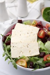Photo of Bowl of tasty salad with tofu and vegetables on white table, closeup