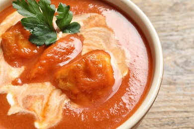 Photo of Bowl of delicious butter chicken on wooden background, closeup. Traditional indian Murgh Makhani