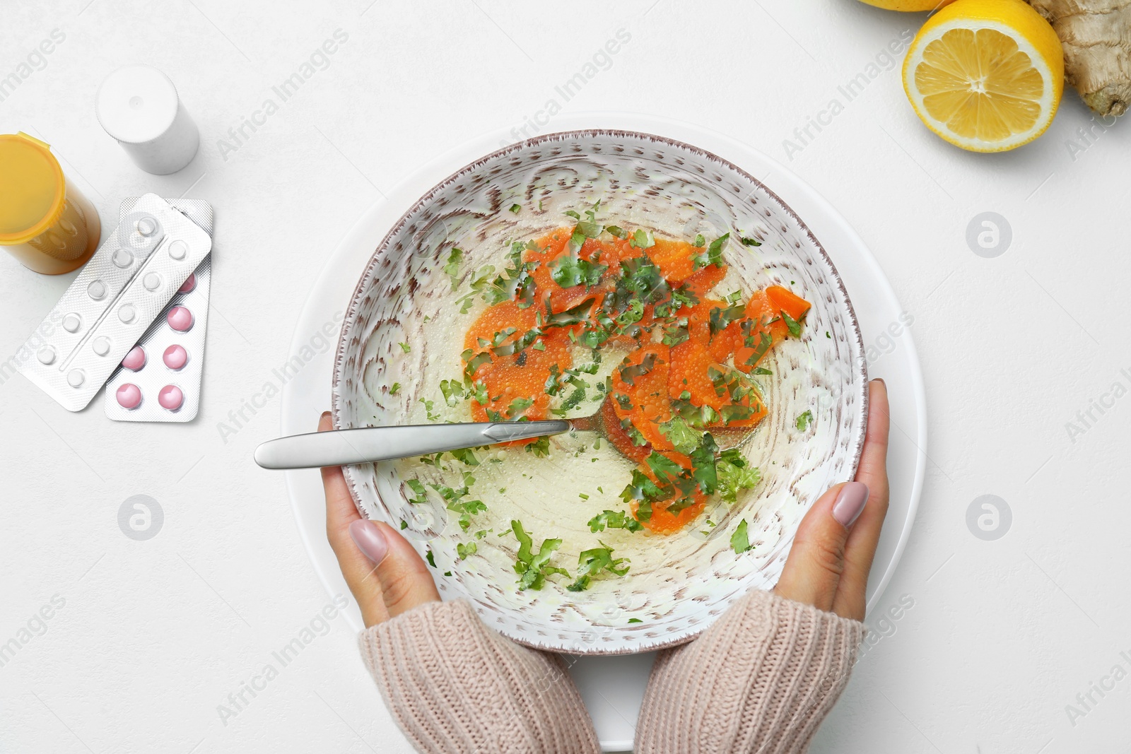 Photo of Woman with bowl of soup at white table, top view. Flu treatment