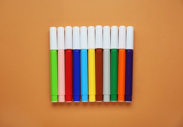 Photo of Different colorful markers on light brown background, flat lay