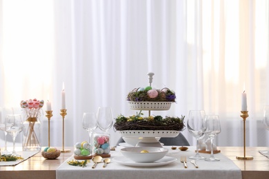 Photo of Beautiful Easter table setting with burning candles and floral decor indoors