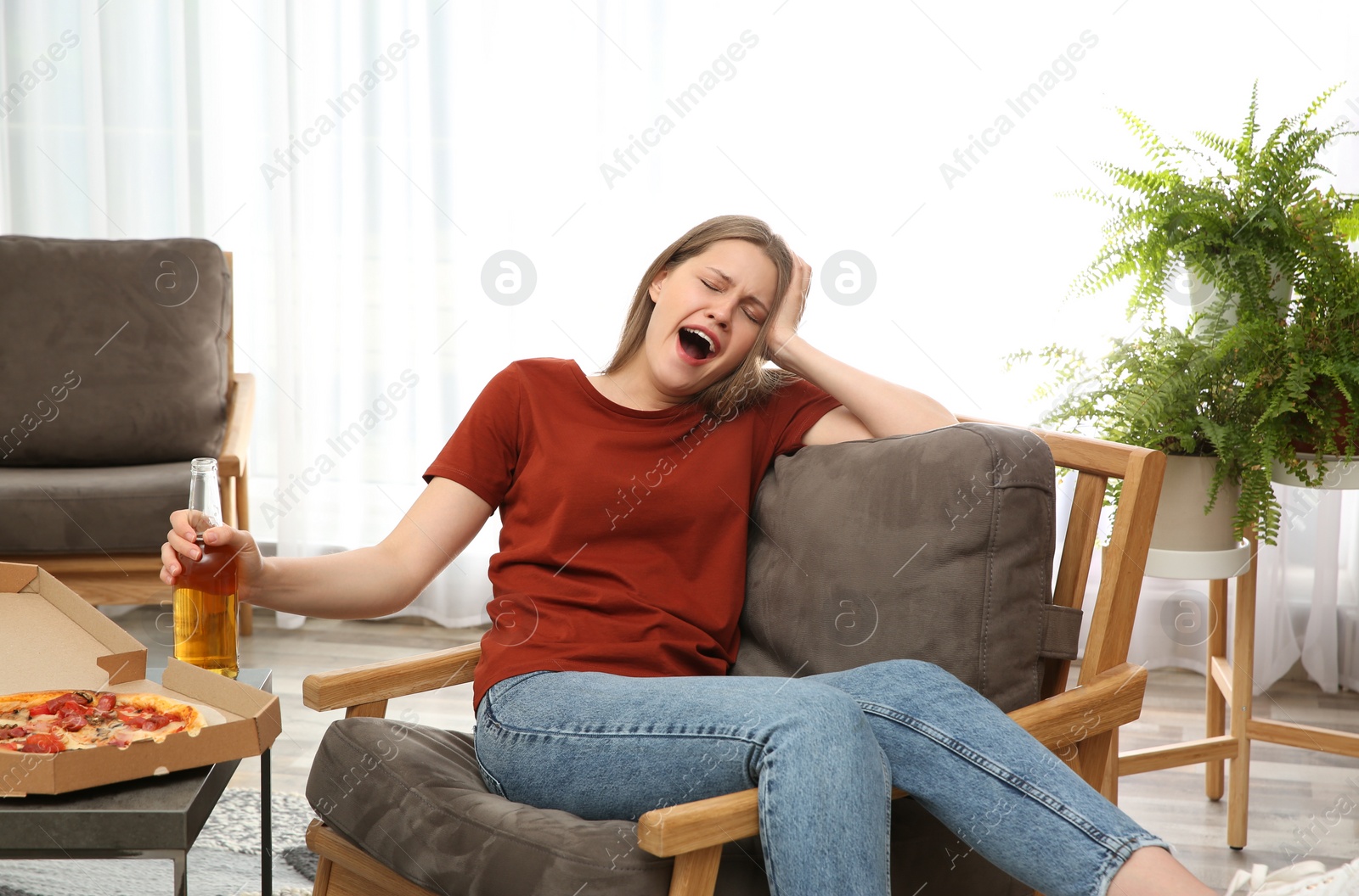 Photo of Lazy young woman with pizza and drink at home