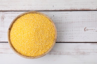 Raw cornmeal in bowl on light wooden table, top view. Space for text
