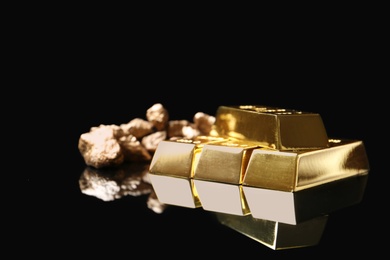 Gold nuggets and ingots on black background