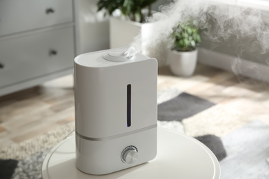Photo of Modern air humidifier on table at home