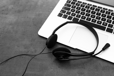 Photo of Modern laptop and headset on table. Technical support concept